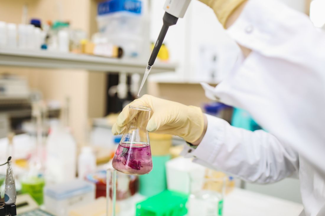 Pipeta dosando ativo em vidraria de laboratório